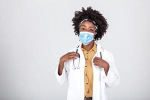 Happy satisfied female African American doctor wearing protective face mask and safety goggles,eyes smiling,studio portrait isolated ,content relief after end of global COVID-19 pandemic crisis photo