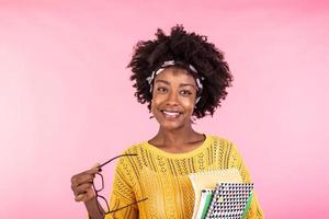 Young african american woman holding notebooks and eyeglasses. Having happy face and smiling photo