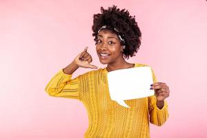 Young and beautiful woman holding white speech bubble board. African american girl wears casual outfit . Emotions and pleasant feelings concept. photo