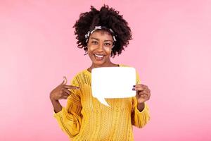 Young and beautiful woman pointing on white speech bubble board. African american girl wears casual outfit . Emotions and pleasant feelings concept. photo