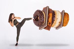 Fit young woman fighting off sweets and candy, Fit young woman saying NO to unhealthy carbohydrates photo