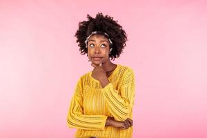 Suspicious annoyed young african american woman with distrustful face looking at camera, skeptical sarcastic black girl feeling cautious dubious distrusting isolated on pink studio background photo
