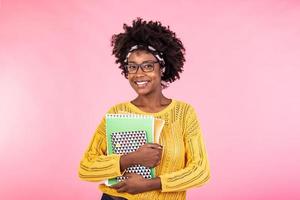 Young female student in glasses holding books in hand isolated on pink background portrait, casual daily lifestyle student holding notebooks smiling photo