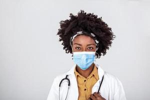 Medicine, profession and healthcare concept - close up of African American female doctor or scientist in protective facial mask over grey background photo