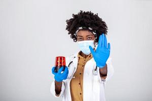 Coronavirus alert. Stop covid 19. Female black doctor holding flasher siren and showing stop sign with her hand to coronavirus photo