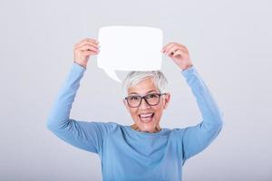 Cheerful mature woman holding speech bubble sign over her head and smiling. Happy senior lady with speech bubble banner Woman showing sign speech bubble banner looking happy photo