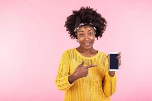 Young woman showing on the telephone. African american woman smiling and pointing finger on smartphone. Concept advertising photo