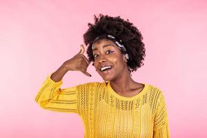 Young beautiful woman doing talking on the telephone gesture and feeling happy. African american woman wearing casual clothes, smiling and looking at camera