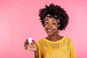 Close up portrait of African American woman holding menstrual cup isolated over purple studio background, happy female, having period, dislike to use napkins or tampons photo