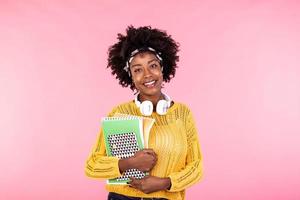 Young female student in glasses holding books in hand isolated on pink background portrait, casual daily lifestyle student holding notebooks smiling