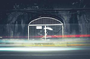 Old dark tunnel with a closed iron gate and light trails. photo