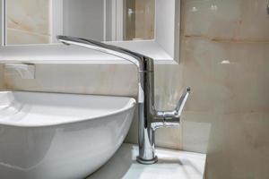 metal water tap with sink and faucet to turn on and regulate cold or hot water in expensive bathroom. photo