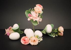 Pastel flowers with white easter eggs on the dark background photo