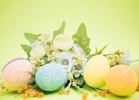 Bouquet made of easter eggs and colorful flowers on a bright green background photo