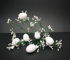 Easter aestethic concept with white eggs and flowers on the black background photo