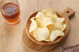 Keripik Singkong or Cassava Chips, Indonesian traditional snack. Served in bowl on wooden background. photo