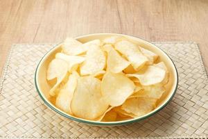 Keripik Singkong or Cassava Chips, Indonesian traditional snack. Served in bowl on wooden background. photo