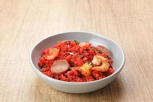 Nasi Goreng Merah, traditional food from Makassar, Indonesia. Fried rice with tomato sauce, shrimp, meatballs and egg. Served with pickled cucumber, chili sauce and lime photo
