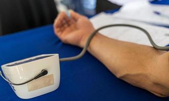 Close-up view of doctor hand measuring blood pressure by strapping device to patient's arm. photo