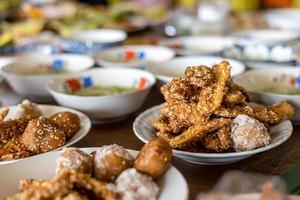 Many delicious fried banana snacks packed in plates placed amongst other Thai desserts. photo