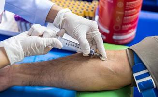 Close-up view, a nurse wearing white latex gloves is using a syringe to puncture a major artery. photo