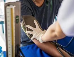 de cerca ver de médico mano medición sangre presión por fornido dispositivo a del paciente brazo. foto