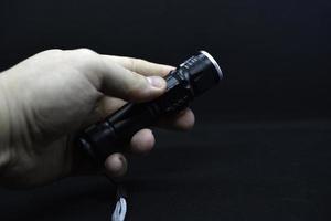 Metal black flashlight in hand. Pocket flashlight. photo