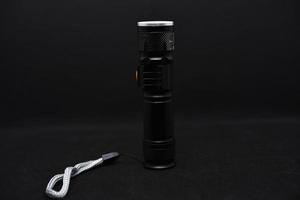 Metal black flashlight on a black background. Pocket flashlight. photo