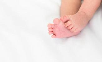 Tiny foot of newborn baby on white blanket at home photo