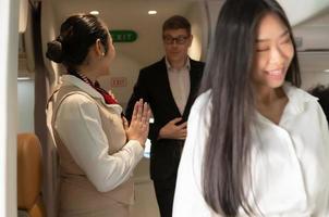 Stewardess greeting passengers while they leaving boarding after flight photo