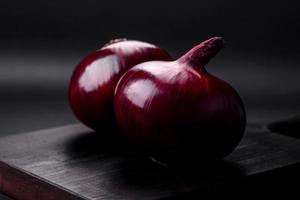 Fresh raw red onion on dark textured concrete background photo