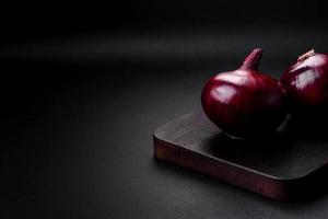 Fresh raw red onion on dark textured concrete background photo