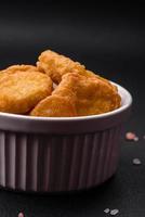 Delicious crispy chicken nuggets with salt and spices on a dark concrete background photo