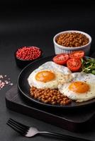 delicioso abundante desayuno consistente de dos frito huevos, Enlatado lentejas y microgreens foto