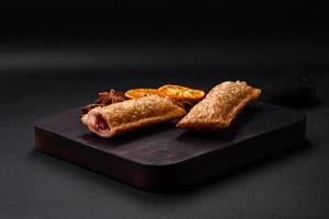 Delicious fresh crispy pie with cherry jam on a wooden cutting board photo