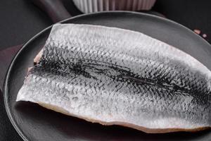 Delicious salted herring fillet in oil on a black ceramic plate photo