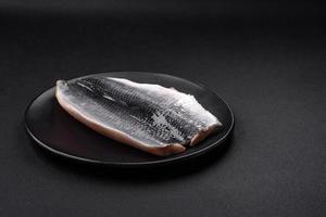 Delicious salted herring fillet in oil on a black ceramic plate photo