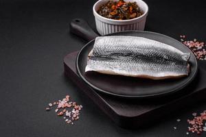 Delicious salted herring fillet in oil on a black ceramic plate photo