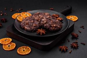 Delicious fresh oatmeal round cookies with chocolate on a black ceramic plate photo