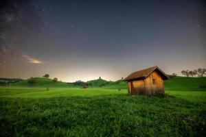 a small hut stands on a meadow sky the milky way can be seen photo