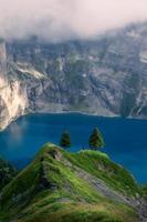 A blue mountain lake surrounded by mountains, a person stand in the distance photo