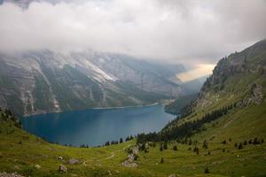 A mountain lake Oeschinensee under a cloudy sky, A big sunbeam breaks through the clouds photo