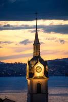 un iluminado Iglesia torre a puesta de sol foto