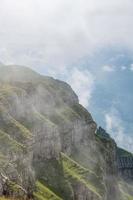 A steep cliff overgrown with grass and hidden by clouds photo