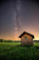 a small hut stands on a meadow sky the milky way can be seen photo