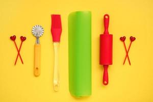 culinario utensilios en un amarillo fondo, silicona laminación alfiler para masa, cepillar, masa cuchillo, brochetas, silicona estera foto