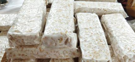 tempe mentah. raw tempeh, uncooked soybean cake from indonesia in a plastic on the table photo