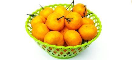 Jeruk Santang Madu. Citrus sinensis. Served in green basket on white background. Free space for text. Often consumed during Chinese New Year. Selected focus. photo