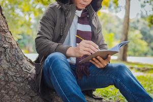 Asian man sitting and writing for a tree photo