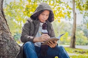 Asian man sitting and writing for a tree photo